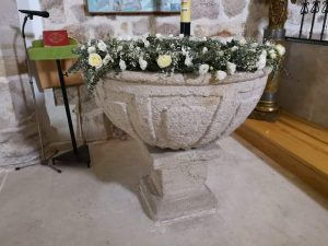 Pila bautismal decorada con una guirnalda de flores para un bautizo